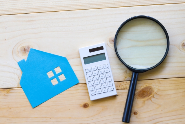 家の模型と電卓と虫眼鏡