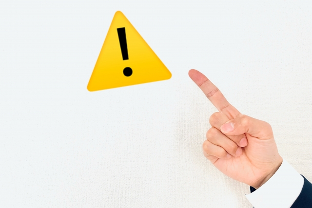 注意マークを指さしている手元