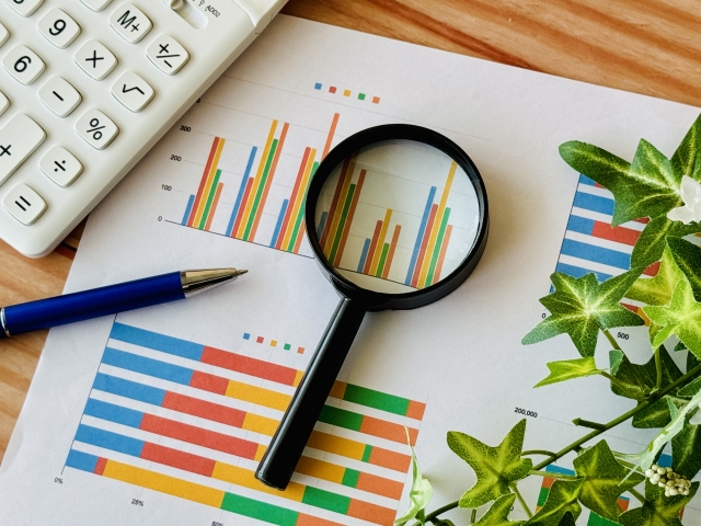 資産グラフと虫眼鏡とボールペン